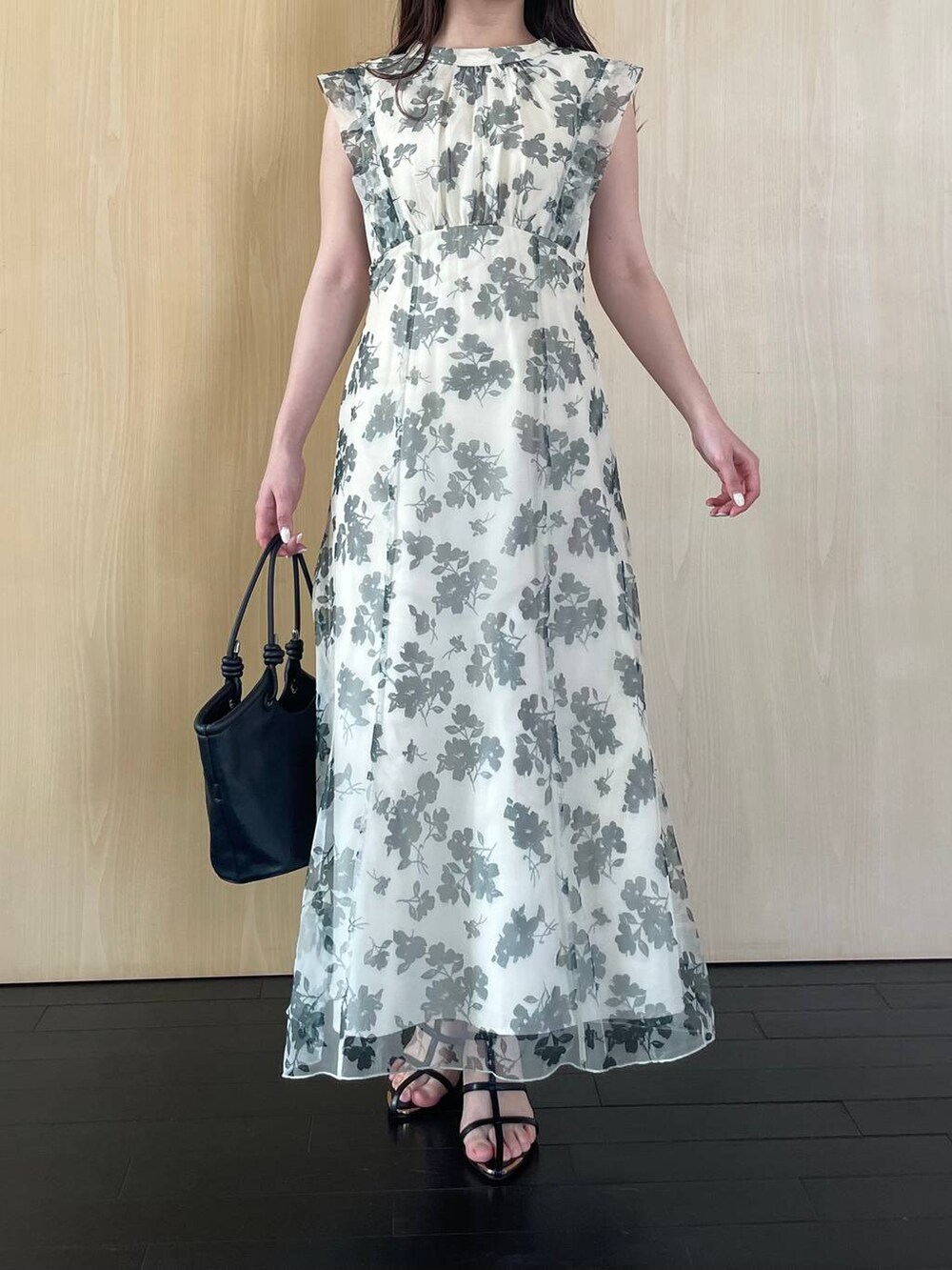 ブラック系のハンドバッグ、ブラック系のサンダル、ホワイト系のワンピースを着用したレディースの春コーディネートの4枚目の写真