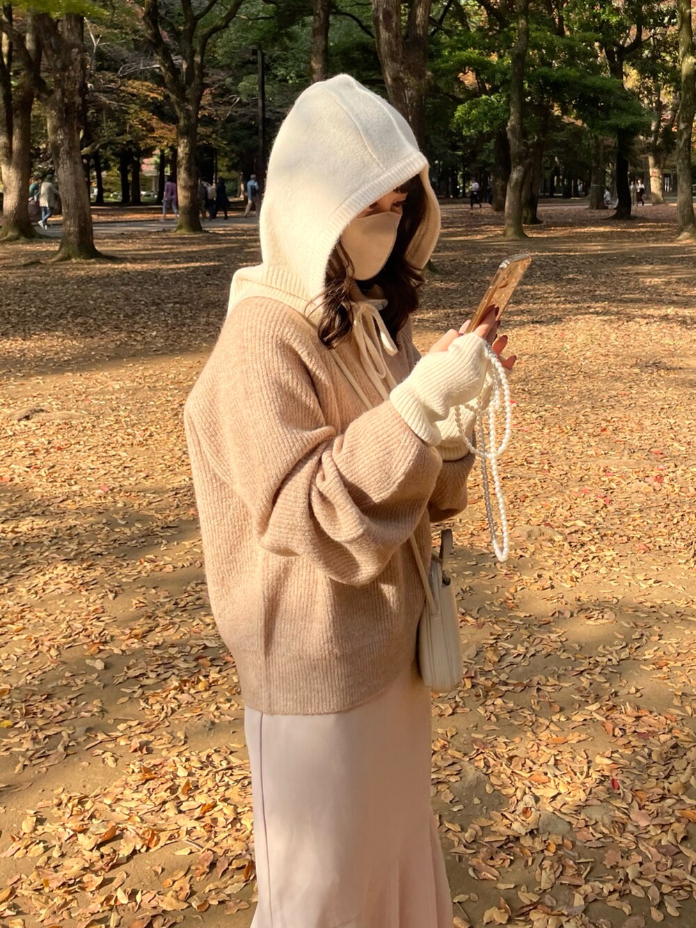 ベージュ系のニット/セーター、ホワイト系のショルダーバッグ、ホワイト系のニットキャップ/ビーニーを着用したレディースの秋コーディネートの3枚目の写真