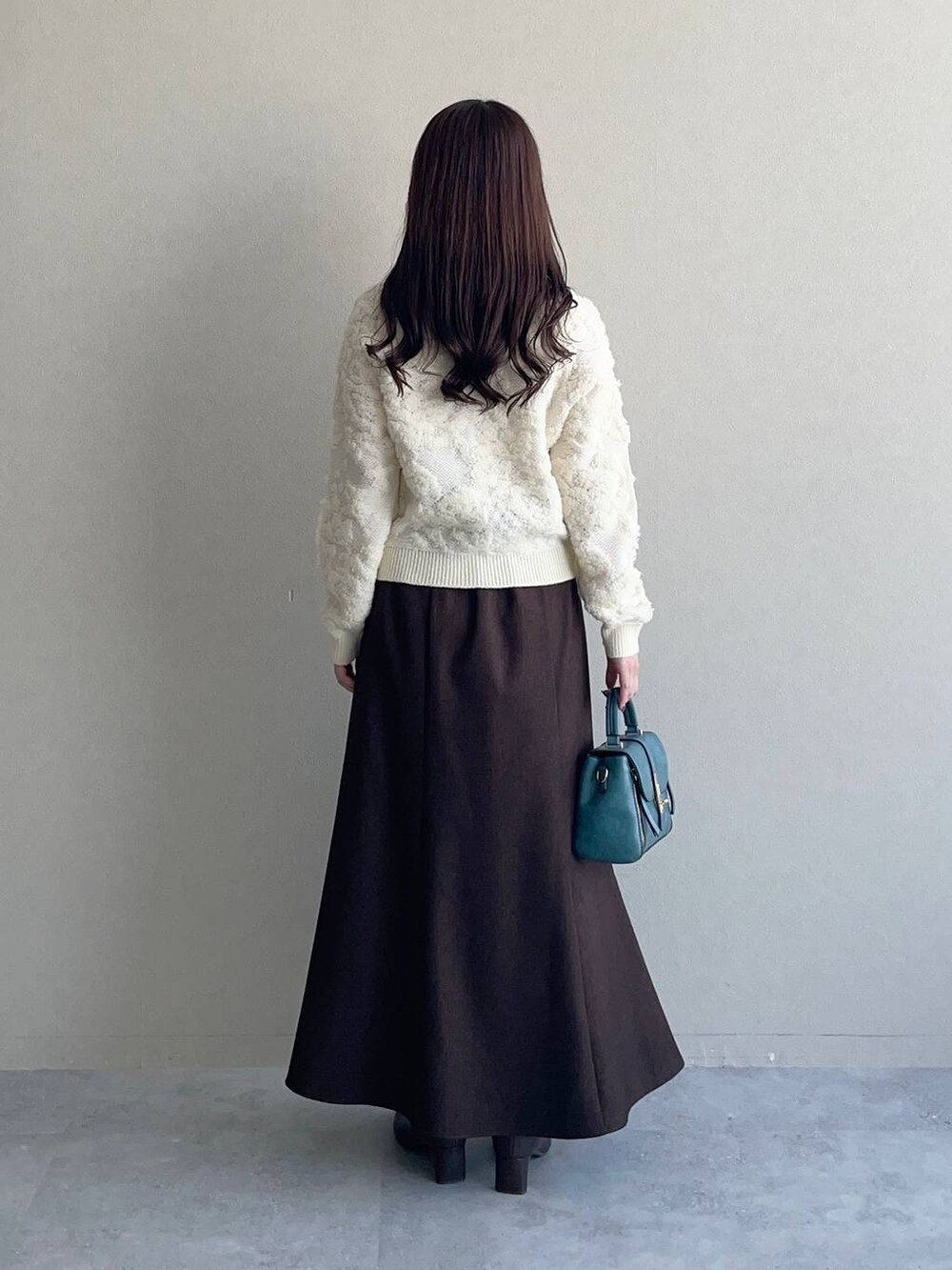 ホワイト系のカーディガン/ボレロ、ブラウン系のスカート、ブラウン系のブーツを着用したレディースの秋コーディネートの2枚目の写真