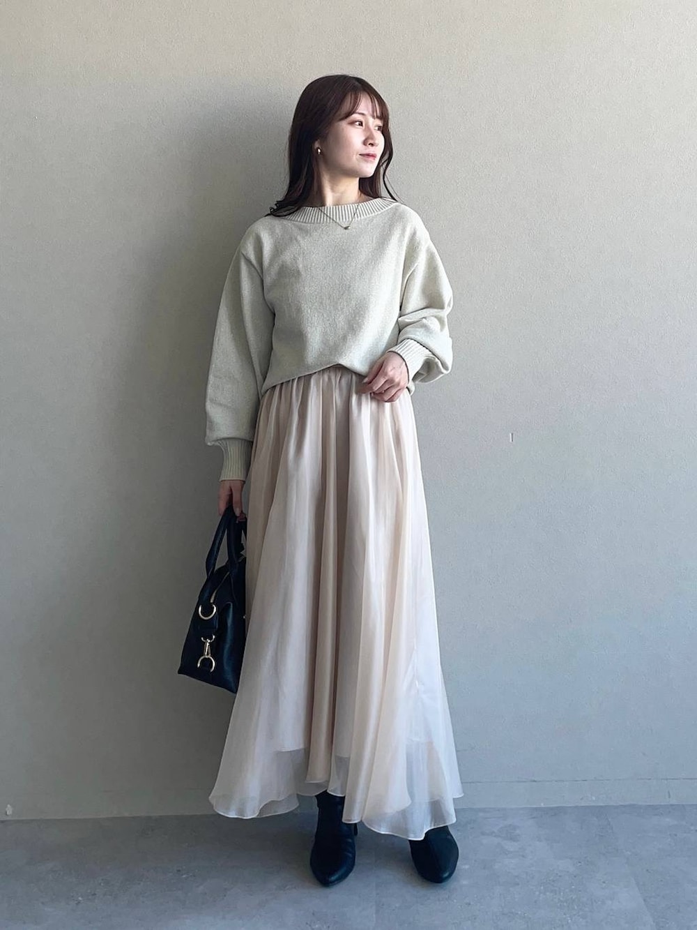 グレー系のピーコート、ホワイト系のニット/セーター、ブラック系のボストンバッグを着用したレディースの冬コーディネートの3枚目の写真