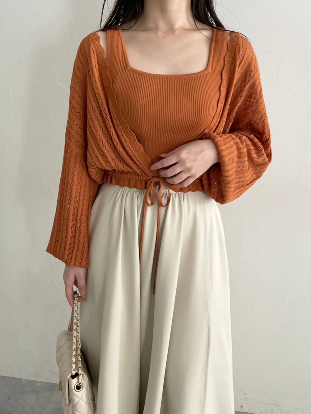 ホワイト系のショルダーバッグ、オレンジ系のカーディガン/ボレロ、ホワイト系のスカートを着用したレディースの夏コーディネートの3枚目の写真