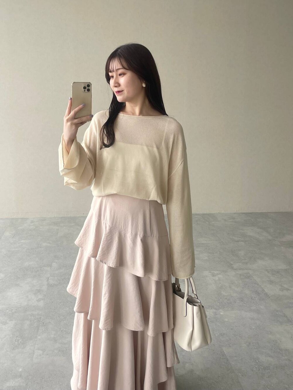 ピンク系のスカート、ホワイト系のニット/セーター、ホワイト系のショルダーバッグを着用したレディースの春コーディネートの3枚目の写真