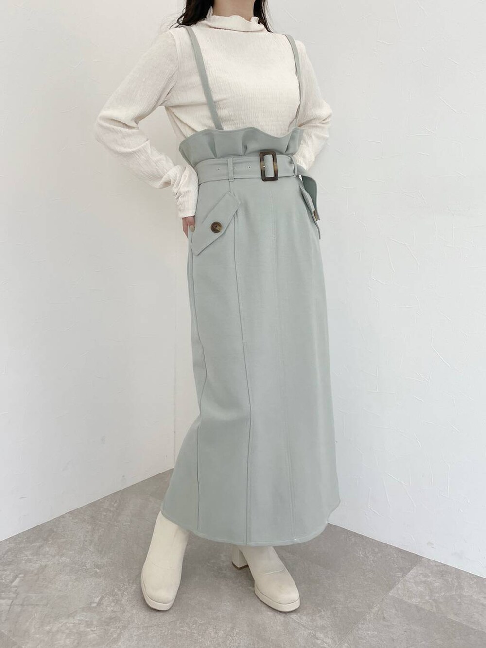 ホワイト系のブーツ、ホワイト系のハンドバッグ、グリーン系のスカートを着用したレディースの冬コーディネートの4枚目の写真