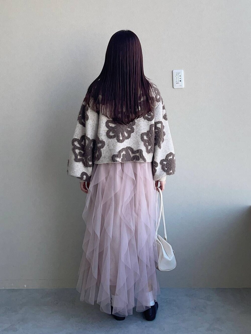 ホワイト系のニット/セーター、ホワイト系のハンドバッグ、ピンク系のスカートを着用したレディースの冬コーディネートの2枚目の写真