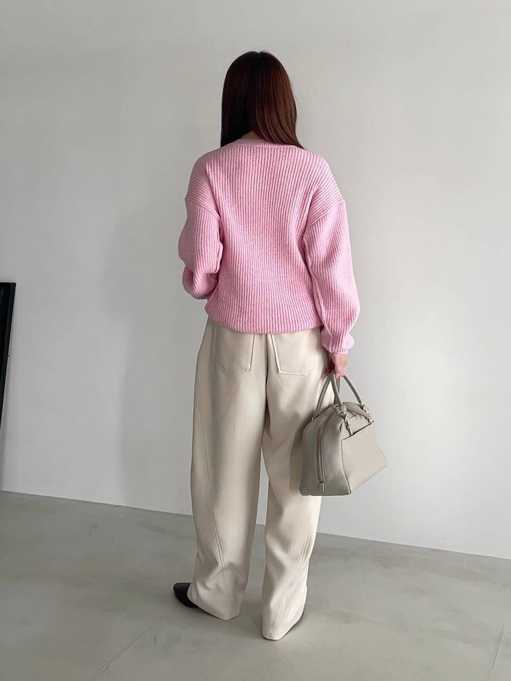 ベージュ系のハンドバッグ、ブラウン系のブーツ、ピンク系のニット/セーターを着用したレディースの冬コーディネートの2枚目の写真