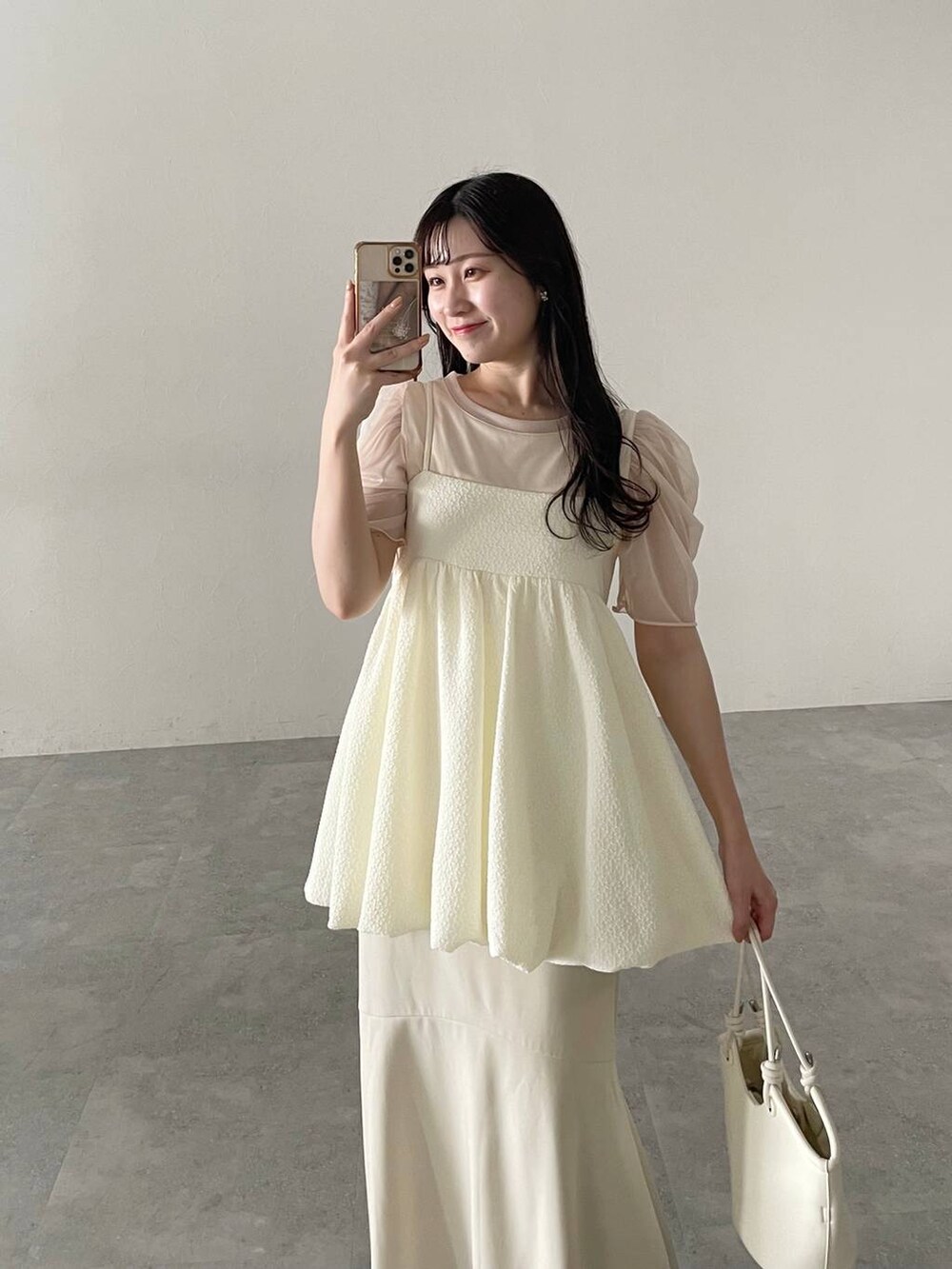 ホワイト系のハンドバッグ、ホワイト系のスカート、ホワイト系のサンダルを着用したレディースの春コーディネートの3枚目の写真