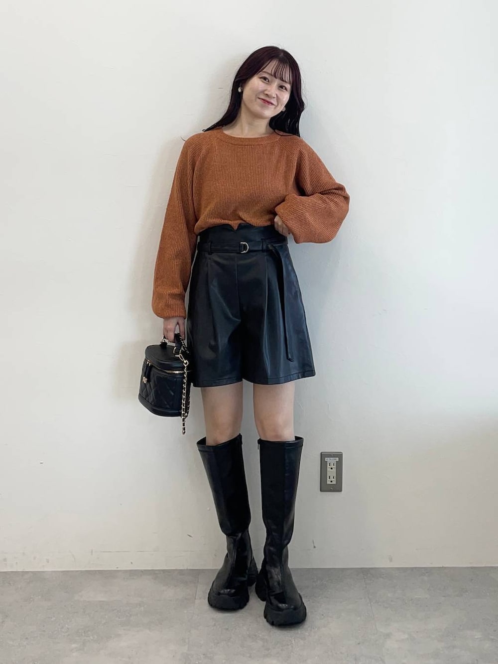ブラック系のブーツ、ブラック系のその他パンツ、オレンジ系のニット/セーターを着用したレディースの秋コーディネートの4枚目の写真