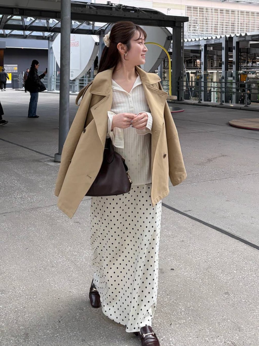 ホワイト系のスカート、ブラウン系のボストンバッグ、ベージュ系のトレンチコートを着用したレディースの冬コーディネートの2枚目の写真