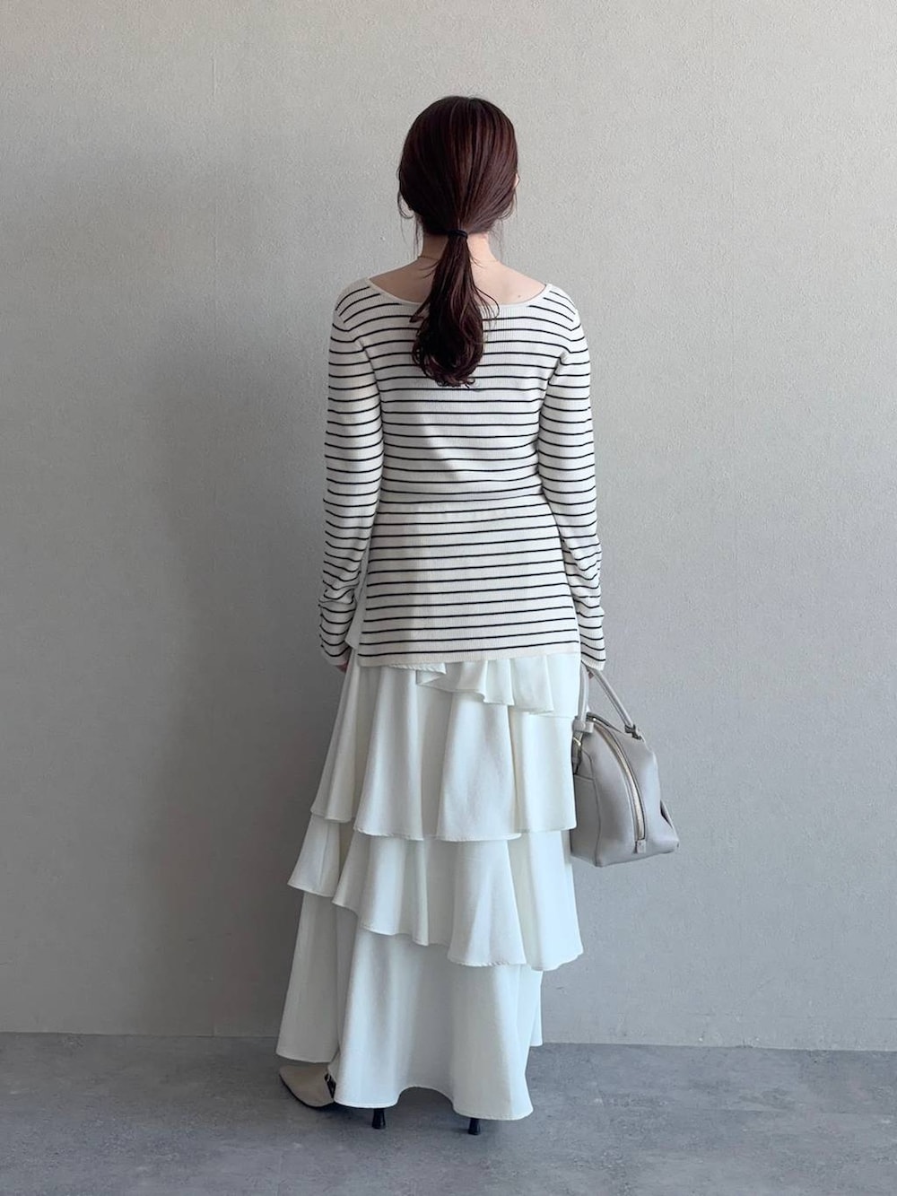 ベージュ系のハンドバッグ、ホワイト系のサンダル、ブルー系のトレンチコートを着用したレディースの冬コーディネートの4枚目の写真