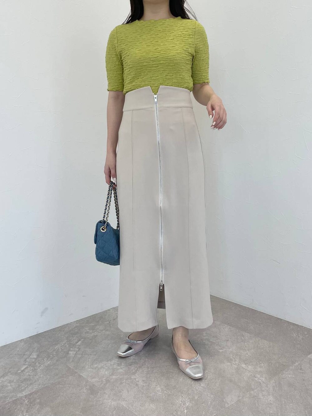 シルバー系のバレエシューズ、ベージュ系のスカート、ブルー系のショルダーバッグを着用したレディースの春コーディネートの4枚目の写真