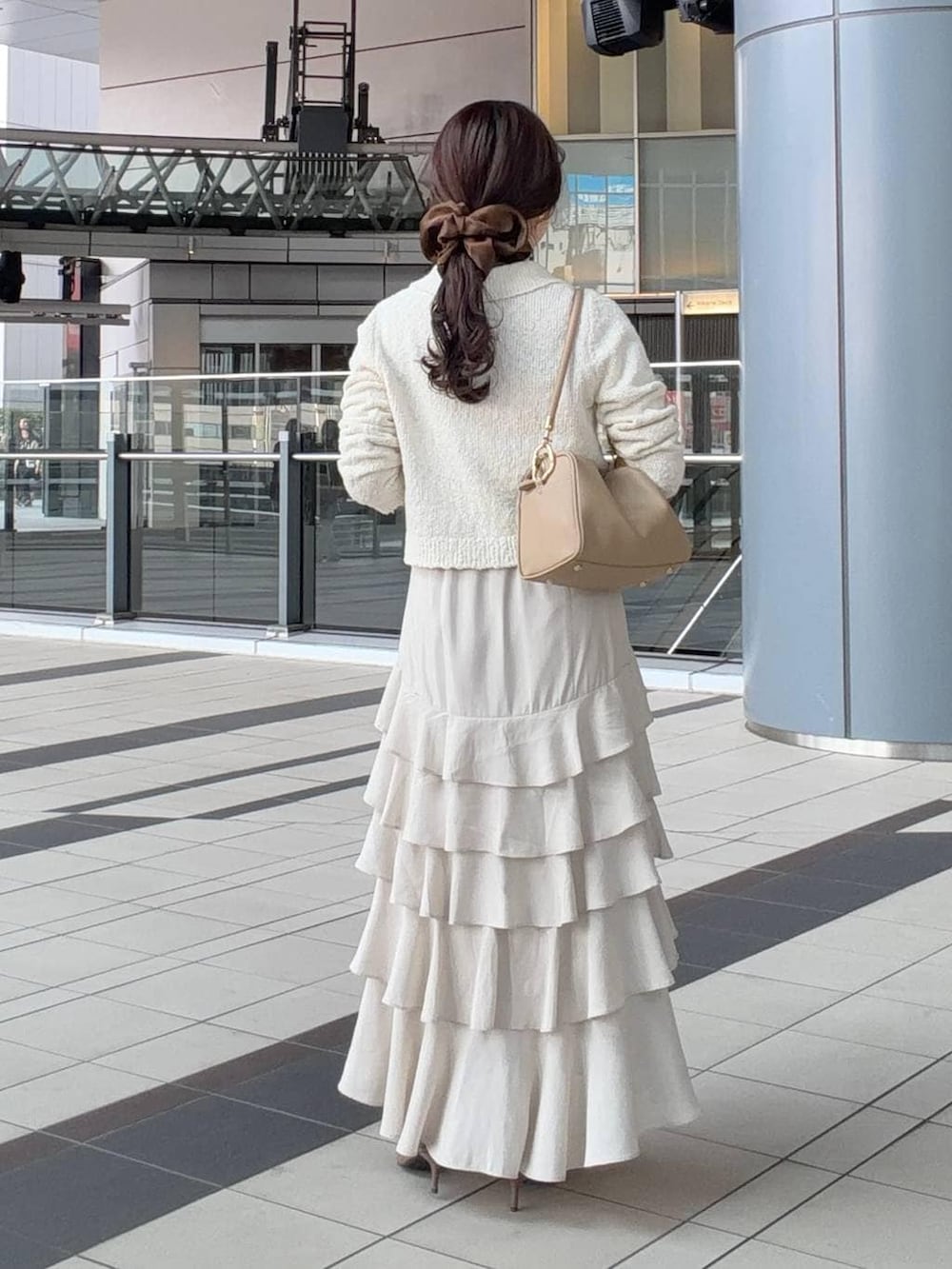 ゴールド系のボストンバッグ、ブラウン系のサンダル、ホワイト系のカーディガン/ボレロを着用したレディースの春コーディネートの2枚目の写真