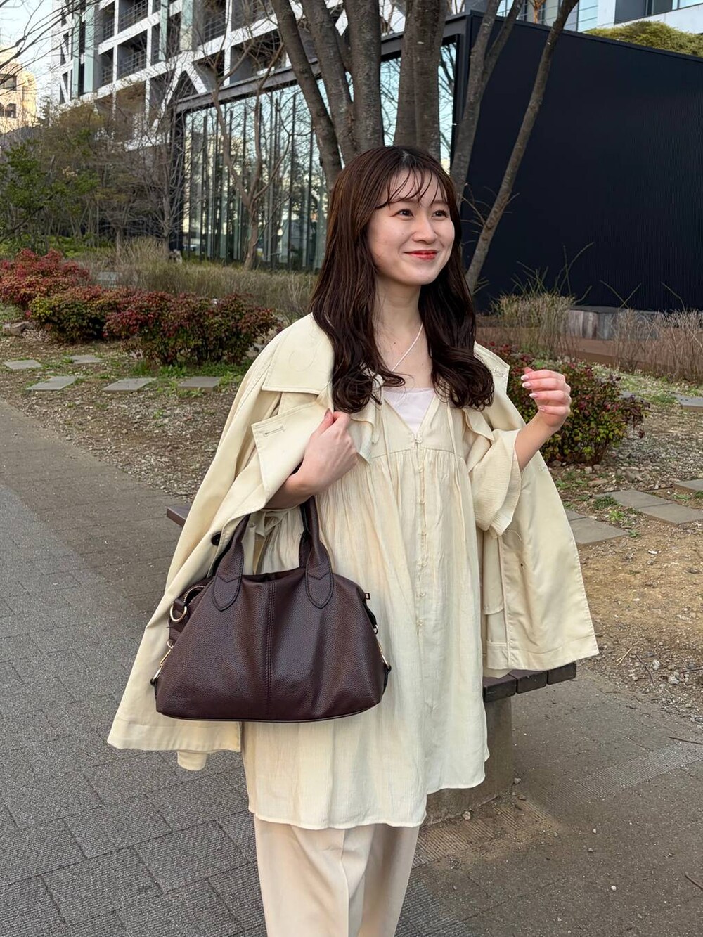 ブラウン系のボストンバッグ、ホワイト系のシャツ/ブラウス、ベージュ系のスラックスを着用したレディースの春コーディネートの3枚目の写真