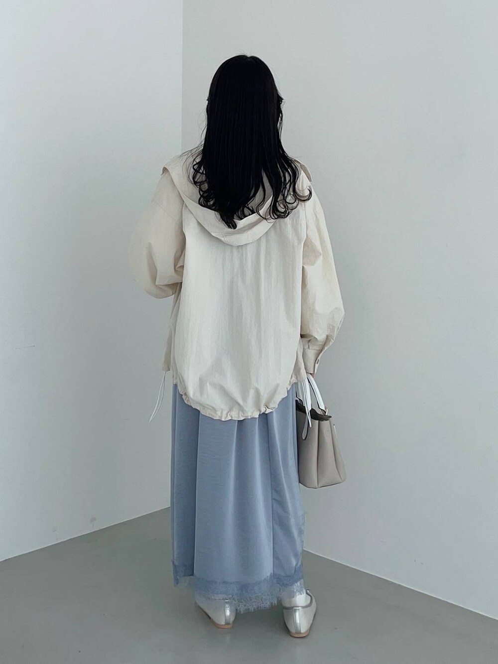 ベージュ系のショルダーバッグ、ホワイト系のマウンテンパーカー、シルバー系のバレエシューズを着用したレディースの春コーディネートの2枚目の写真