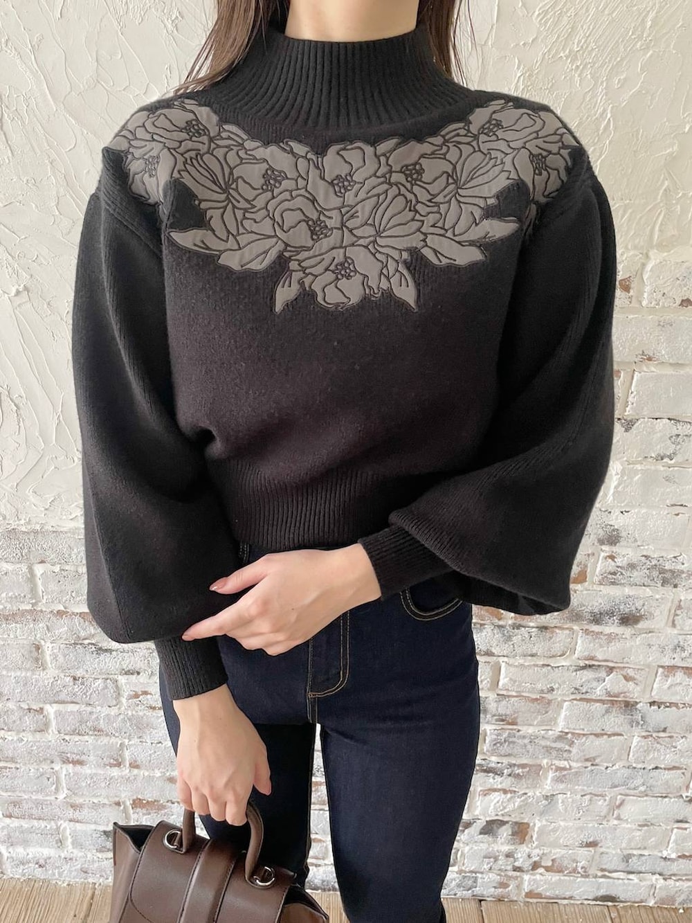 ブルー系のデニムパンツ、ブラウン系のハンドバッグ、ブラック系のブーツを着用したレディースの冬コーディネートの3枚目の写真