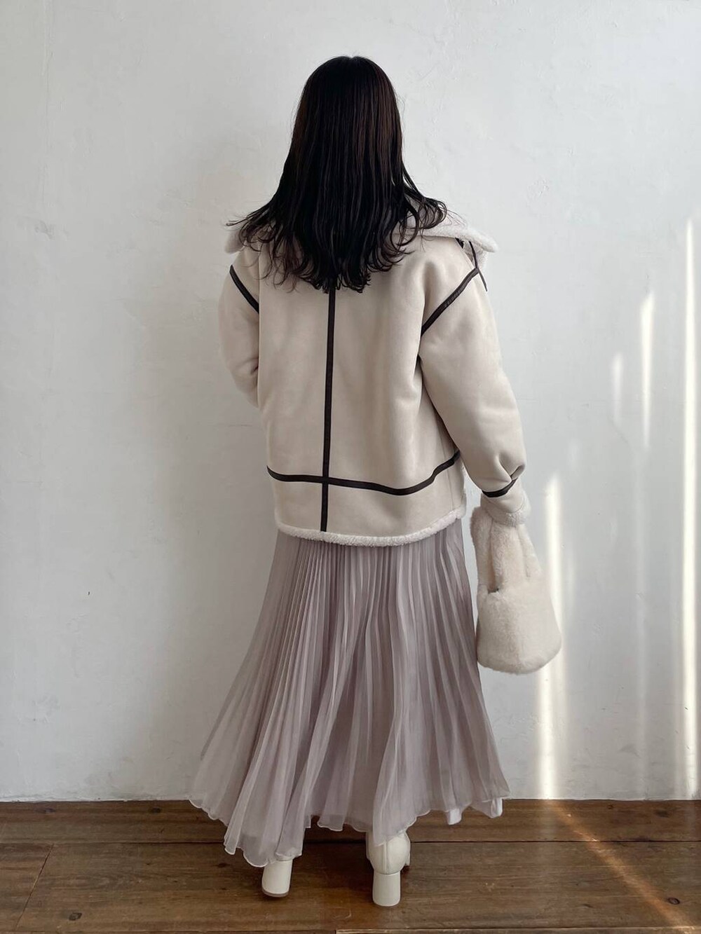 ホワイト系のブーツ、ホワイト系のハンドバッグ、ベージュ系のスカートを着用したレディースの秋コーディネートの2枚目の写真