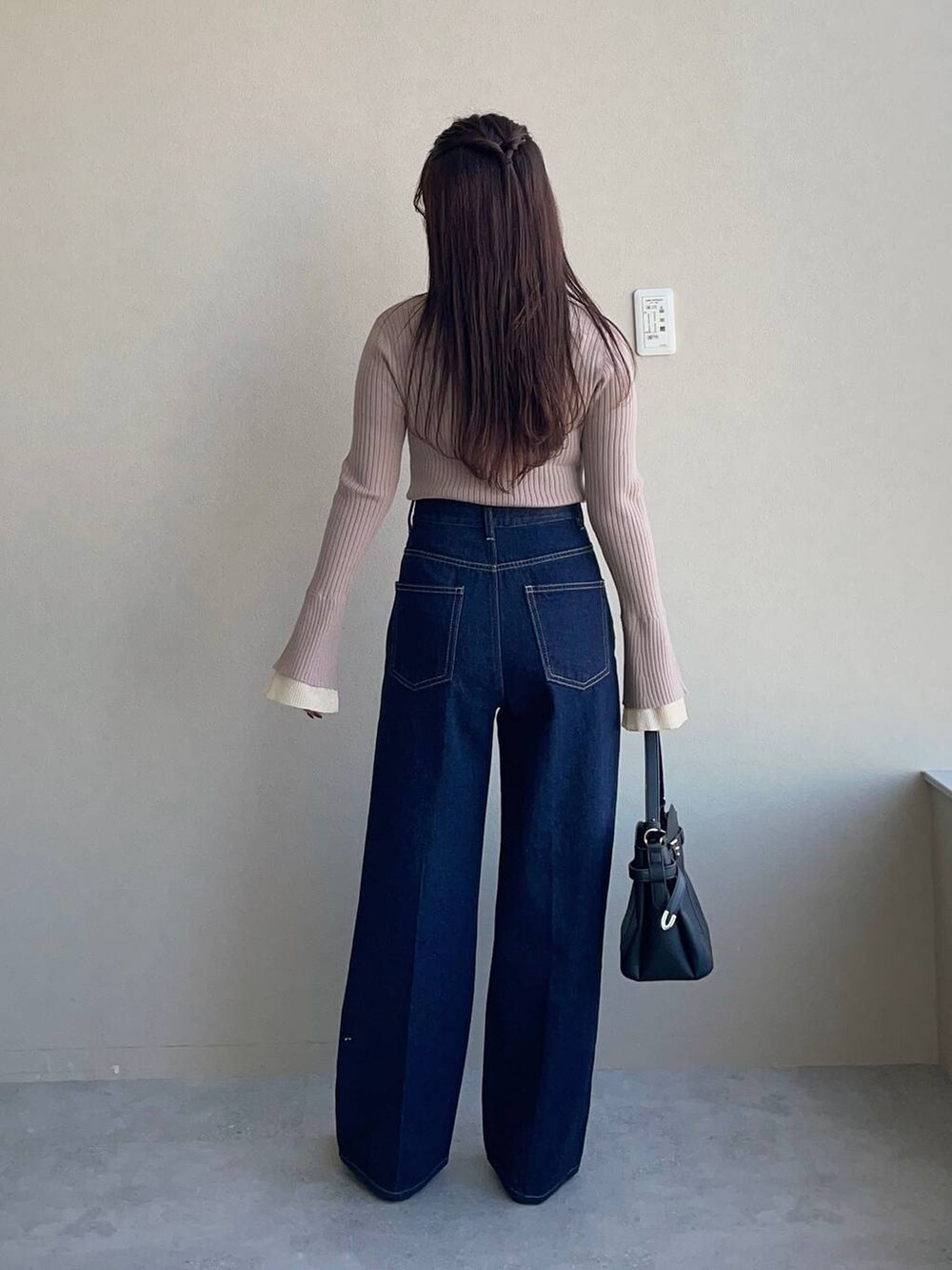 ブラック系のショルダーバッグ、ブルー系のデニムパンツ、ベージュ系のニット/セーターを着用したレディースの冬コーディネートの7枚目の写真
