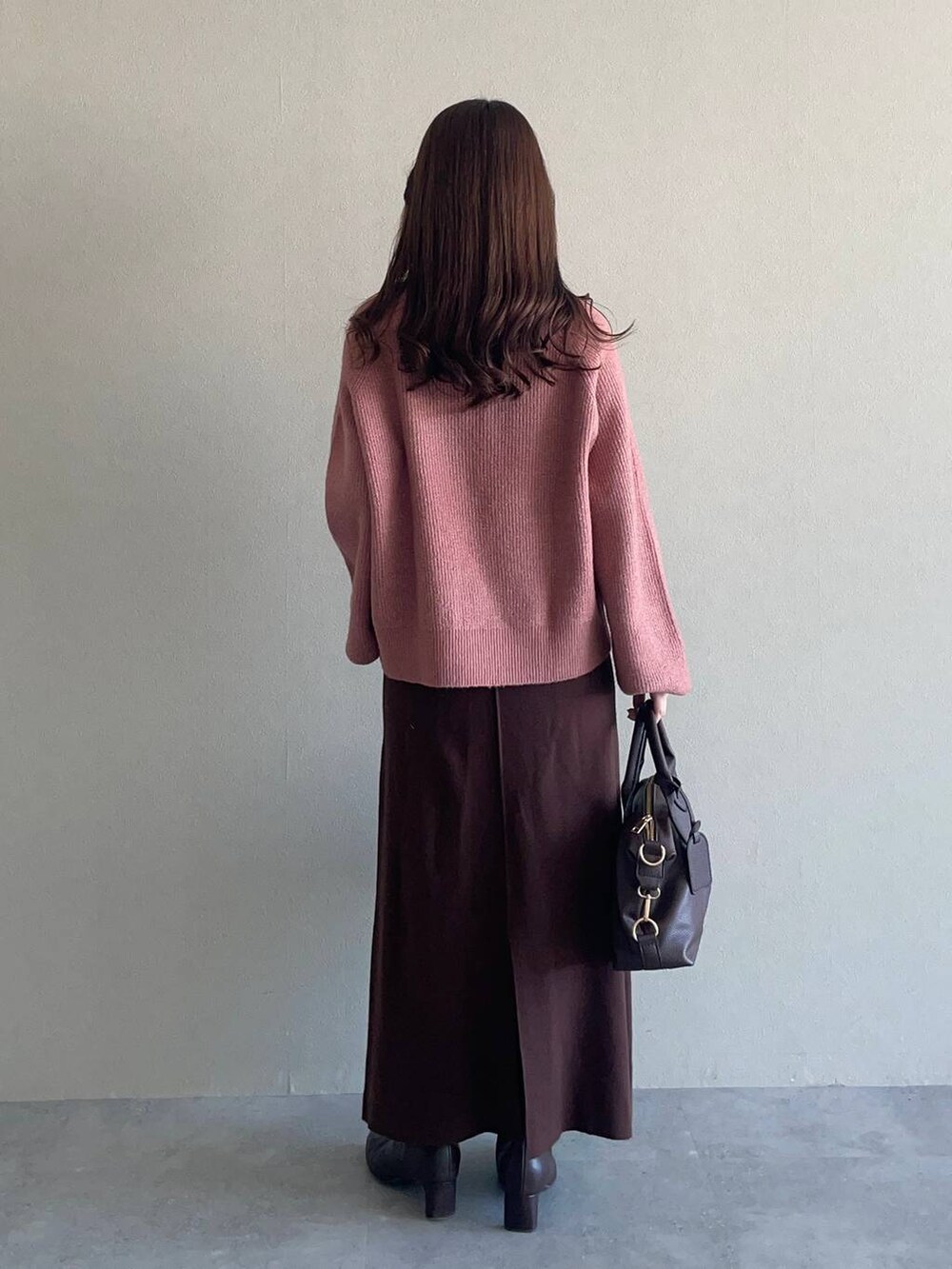 ピンク系のニット/セーター、ブラウン系のボストンバッグ、ホワイト系のチェスターコートを着用したレディースの冬コーディネートの4枚目の写真