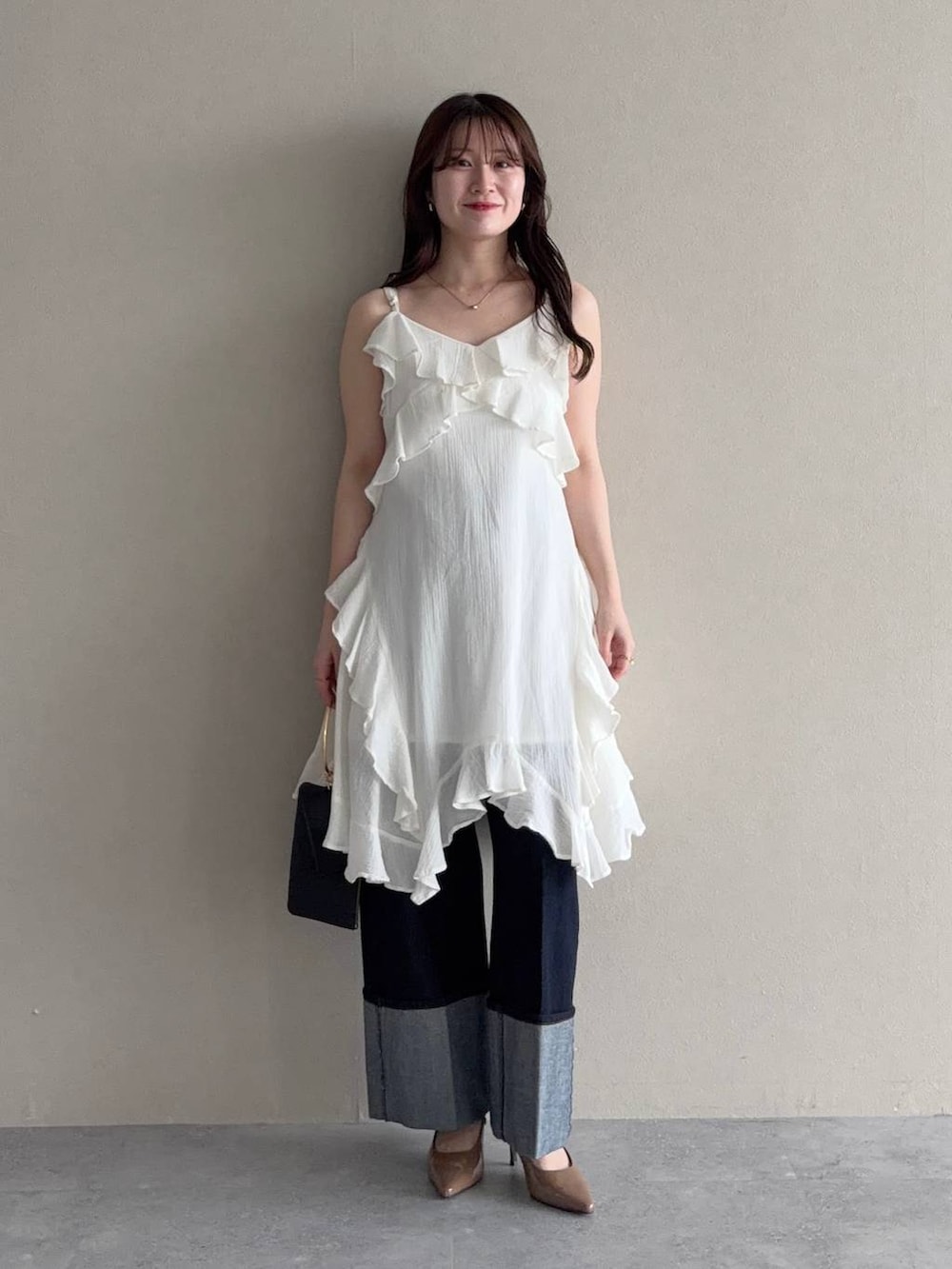 ブラック系のパーカー、ブラウン系のサンダル、ブルー系のデニムパンツを着用したレディースの春コーディネートの3枚目の写真