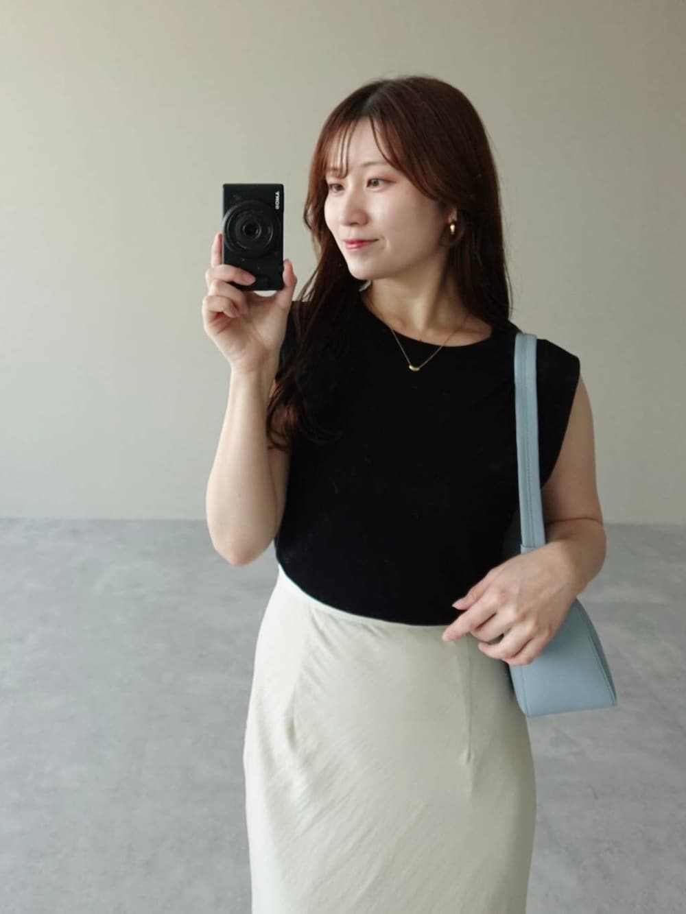 ブラック系のニット/セーター、ホワイト系のスカート、ホワイト系のサンダルを着用したレディースの夏コーディネートの3枚目の写真
