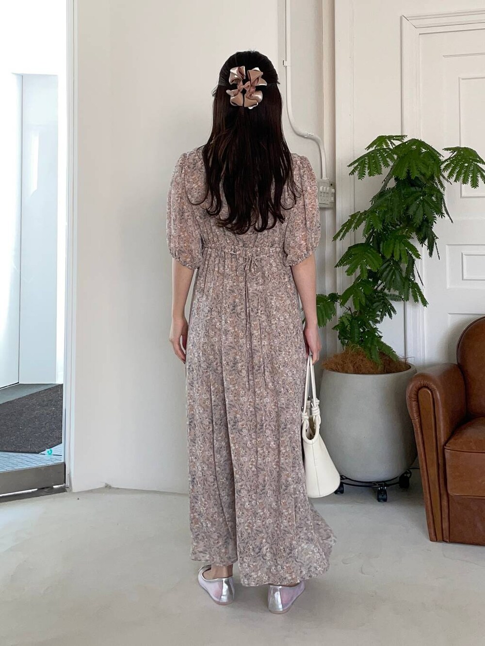 シルバー系のバレエシューズ、ホワイト系のハンドバッグ、ピンク系のワンピースを着用したレディースの夏コーディネートの2枚目の写真