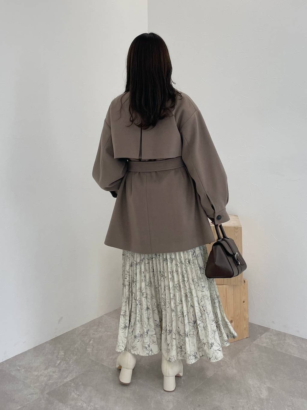 ベージュ系のニット/セーター、ブラウン系のチェスターコート、ブラウン系のハンドバッグを着用したレディースの秋コーディネートの2枚目の写真