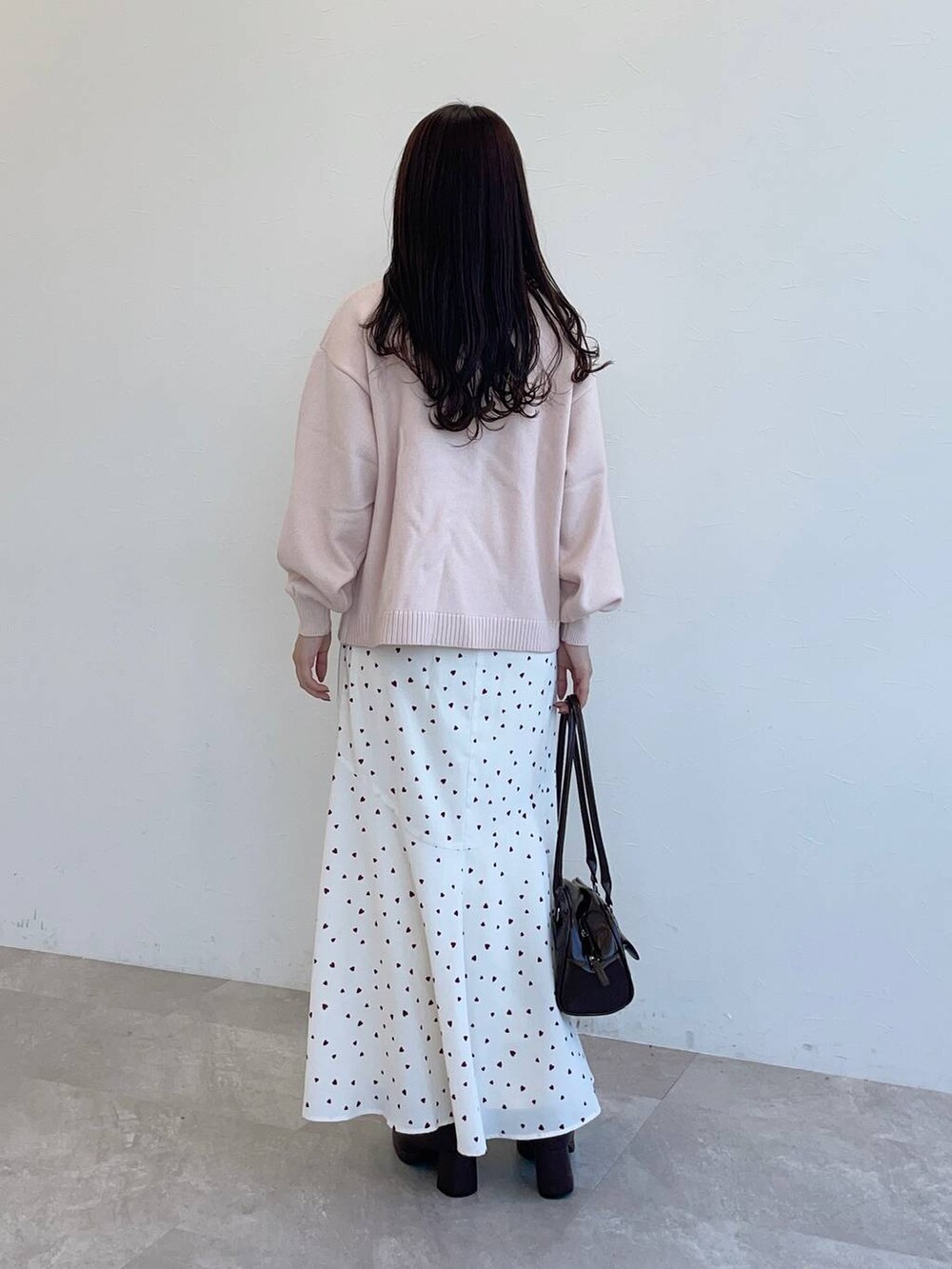 ブラウン系のブーツ、ブラウン系のハンドバッグ、ピンク系のニット/セーターを着用したレディースの秋コーディネートの2枚目の写真