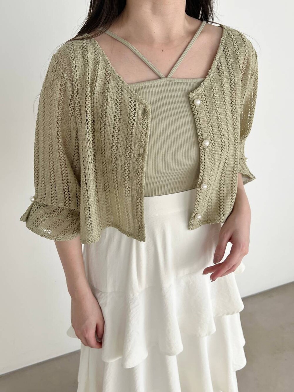 ホワイト系のスカート、ホワイト系のショルダーバッグ、グリーン系のカーディガン/ボレロを着用したレディースの春コーディネートの3枚目の写真