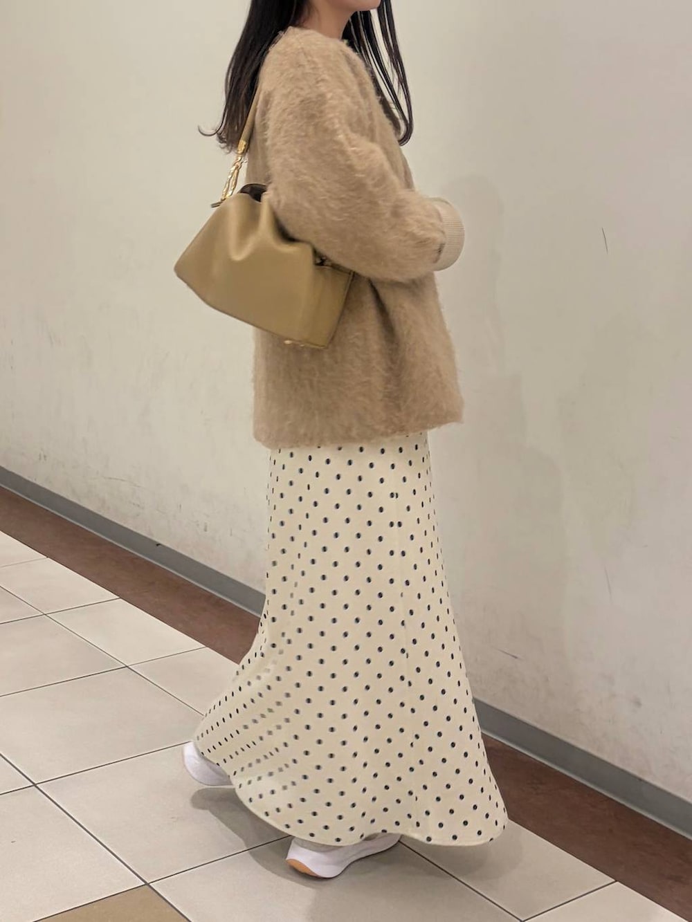 ホワイト系のスカート、ベージュ系のカーディガン/ボレロ、ゴールド系のボストンバッグを着用したレディースの冬コーディネートの3枚目の写真