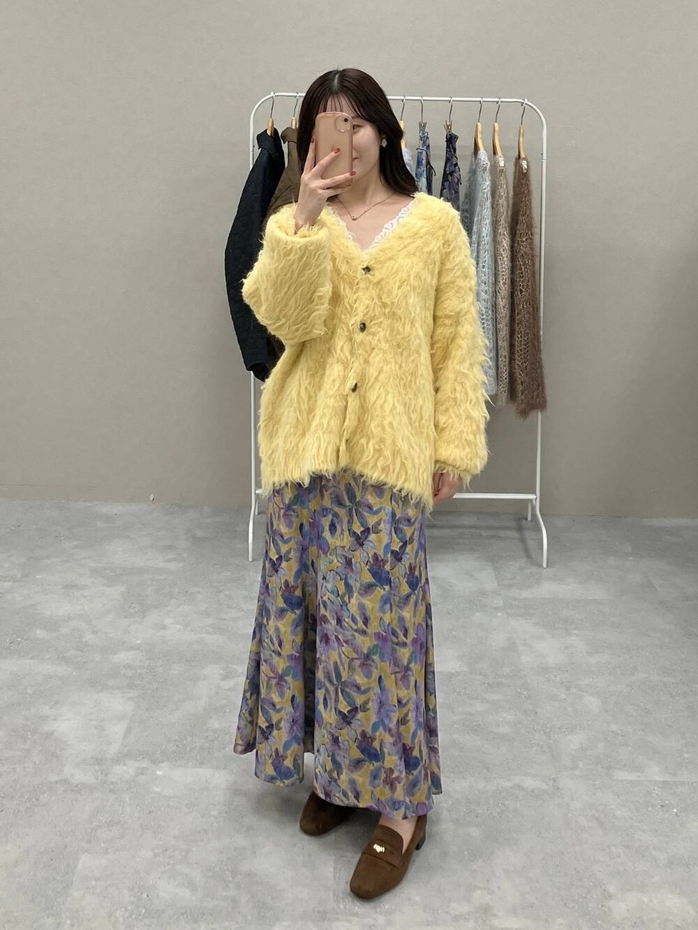 ホワイト系のタンクトップ、イエロー系のカーディガン/ボレロ、イエロー系のスカートを着用したレディースの秋コーディネートの3枚目の写真