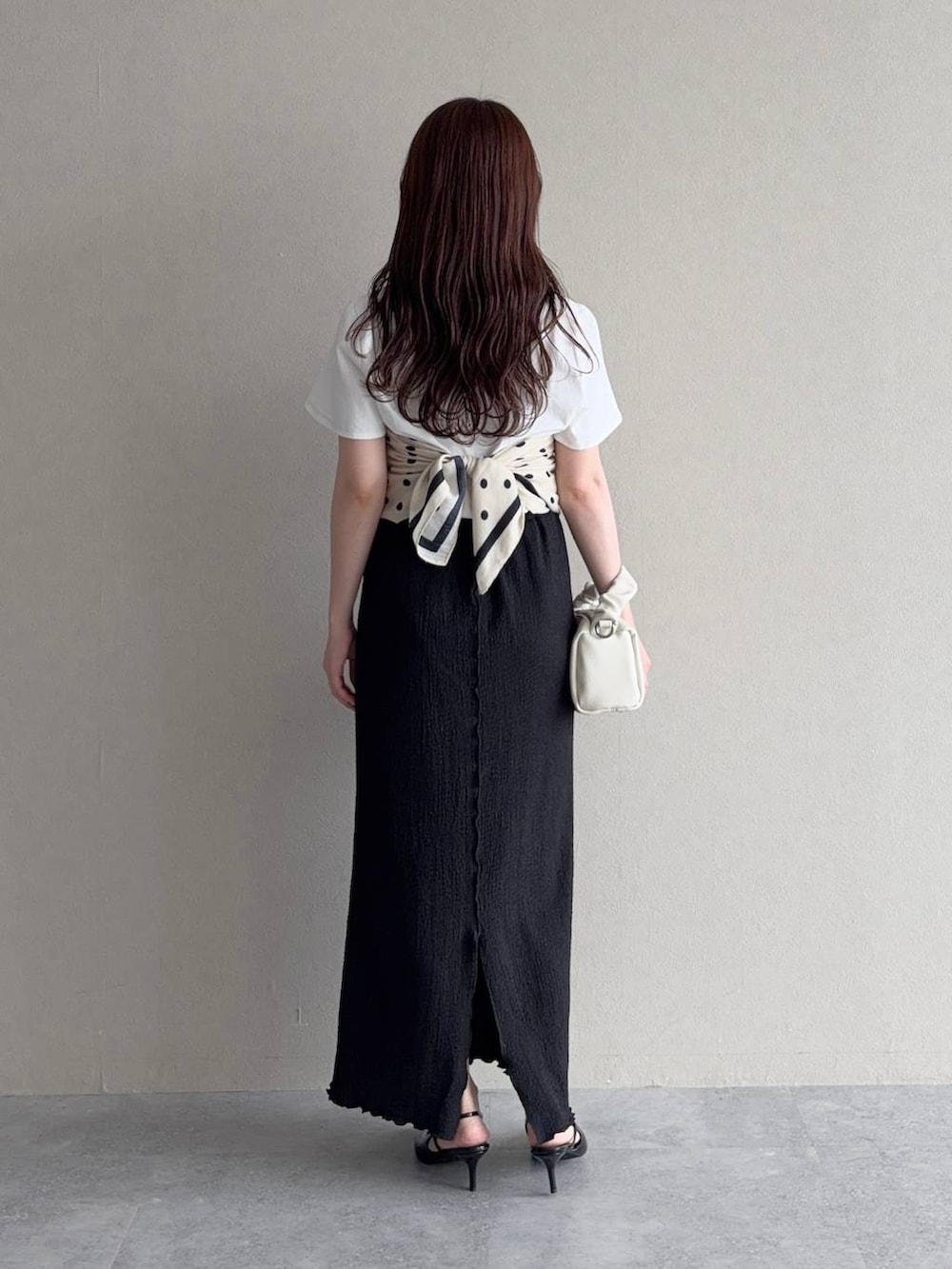 ブラック系のスカート、ブラック系のサンダル、ホワイト系のTシャツ/カットソーを着用したレディースの夏コーディネートの2枚目の写真