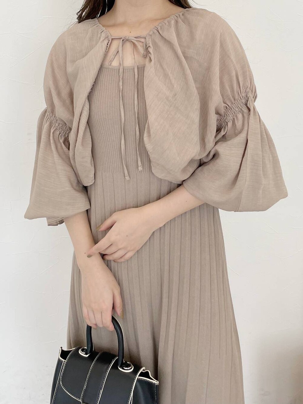 ブラック系のハンドバッグ、グレー系のブーツ、ベージュ系のワンピースを着用したレディースの秋コーディネートの3枚目の写真