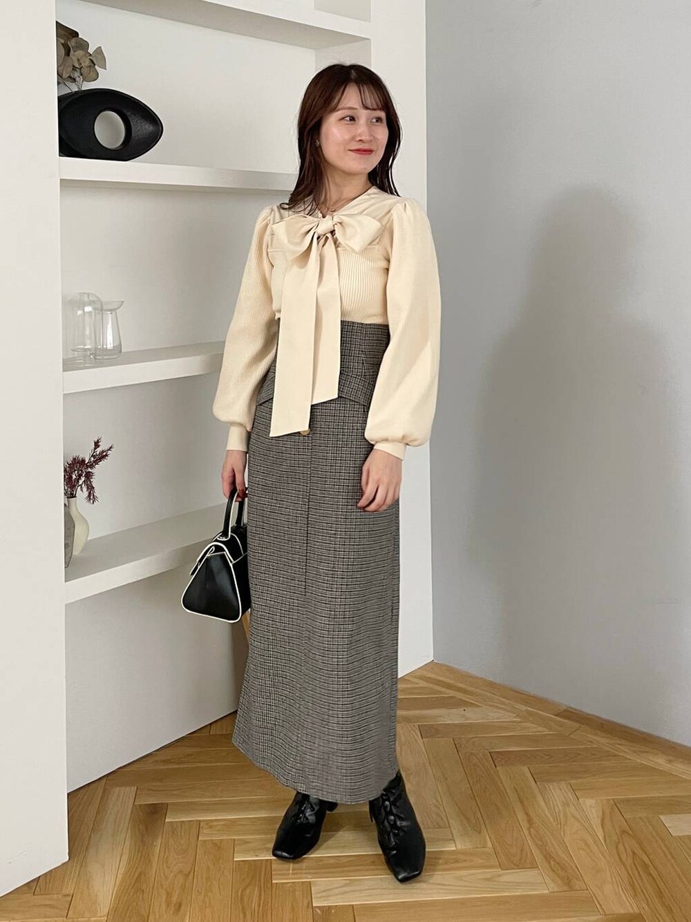 ブラウン系のチェスターコート、ブラック系のハンドバッグ、ブラック系のブーツを着用したレディースの秋コーディネートの3枚目の写真