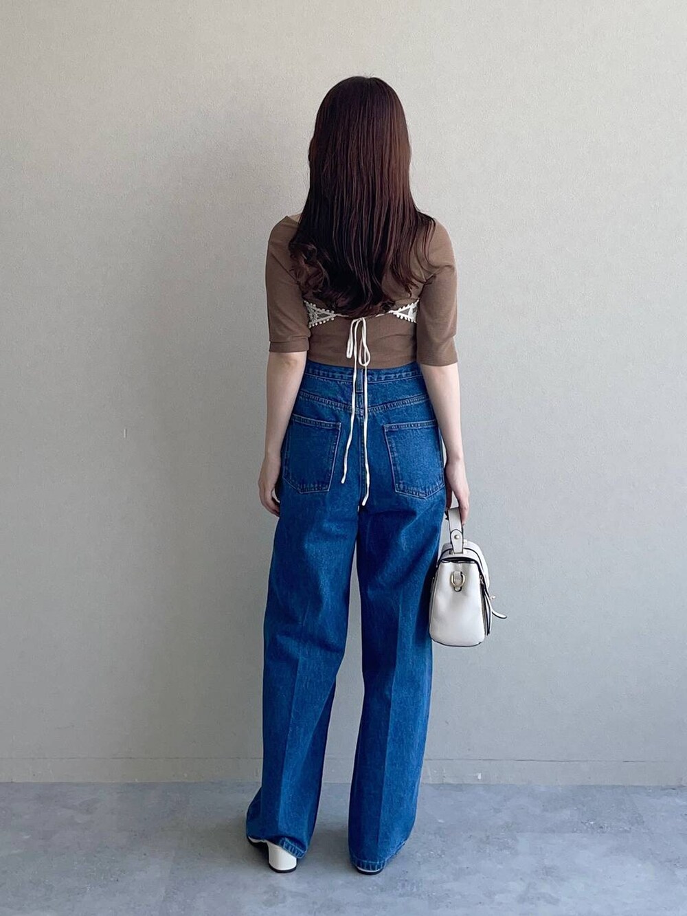 ホワイト系のショルダーバッグ、ブラウン系のTシャツ/カットソー、ブルー系のデニムパンツを着用したレディースの秋コーディネートの2枚目の写真