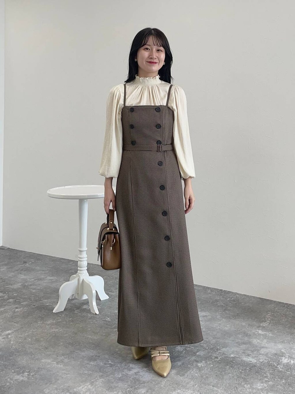 ゴールド系のパンプス、ブラウン系のショルダーバッグ、ホワイト系のシャツ/ブラウスを着用したレディースの秋コーディネートの3枚目の写真