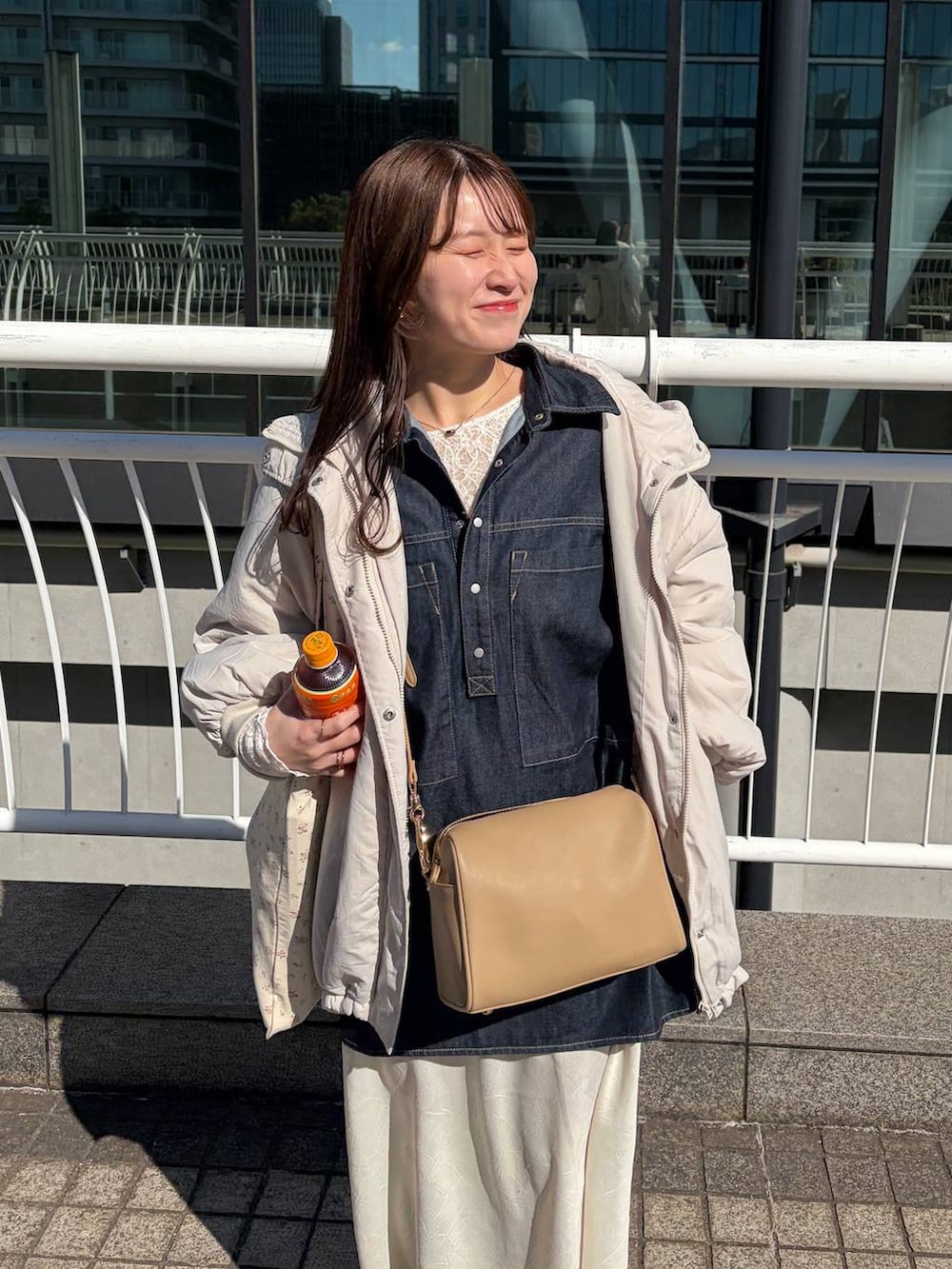 ホワイト系のスカート、ゴールド系のボストンバッグ、ホワイト系のTシャツ/カットソーを着用したレディースの冬コーディネートの2枚目の写真