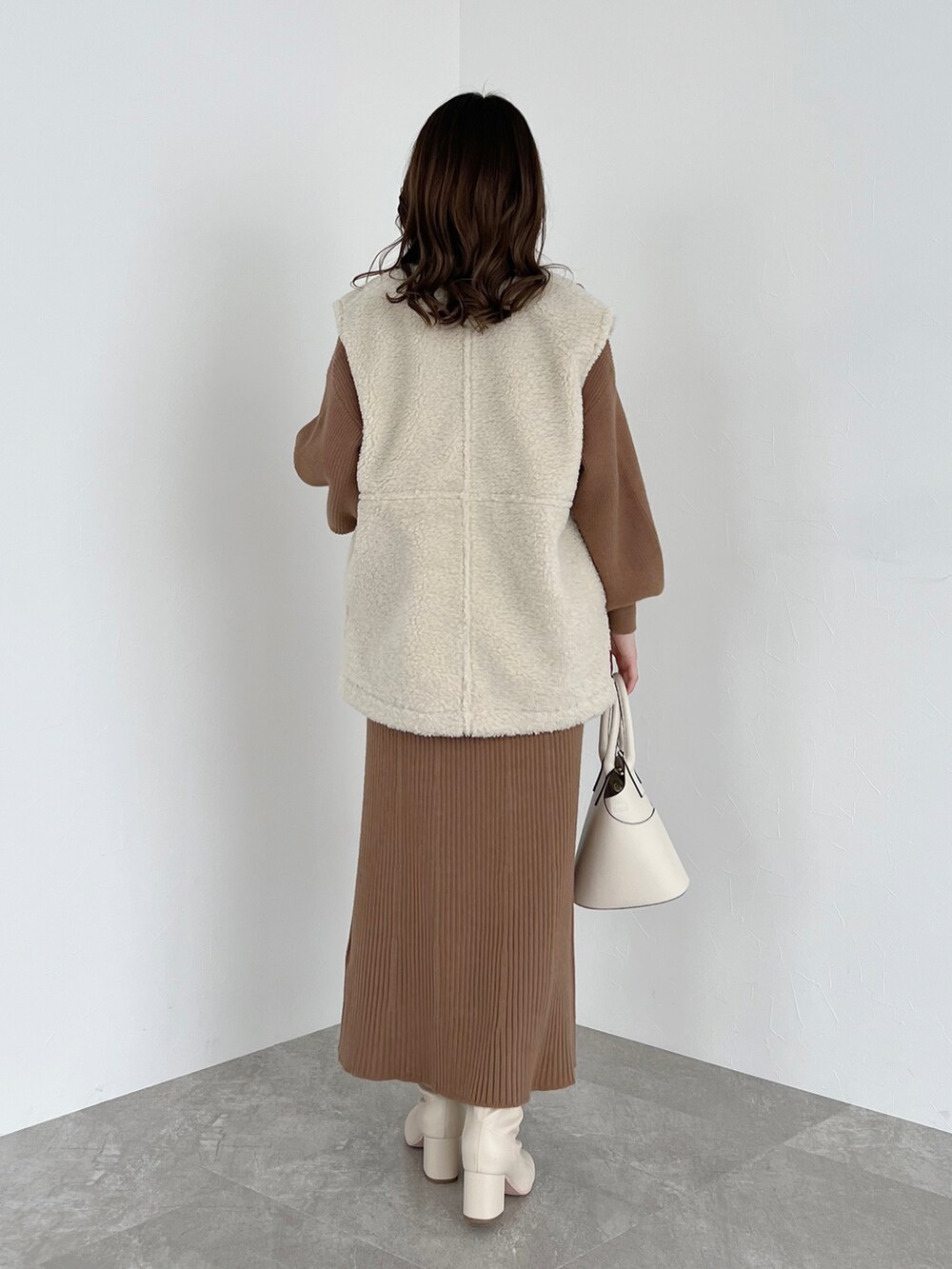 ホワイト系のショルダーバッグ、ホワイト系のブーツ、ホワイト系のその他アウターを着用したレディースの冬コーディネートの2枚目の写真