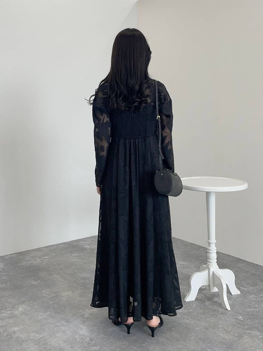 ブラック系のワンピース、ブラック系のパンプス、ブラック系のショルダーバッグを着用したレディースの秋コーディネートの2枚目の写真