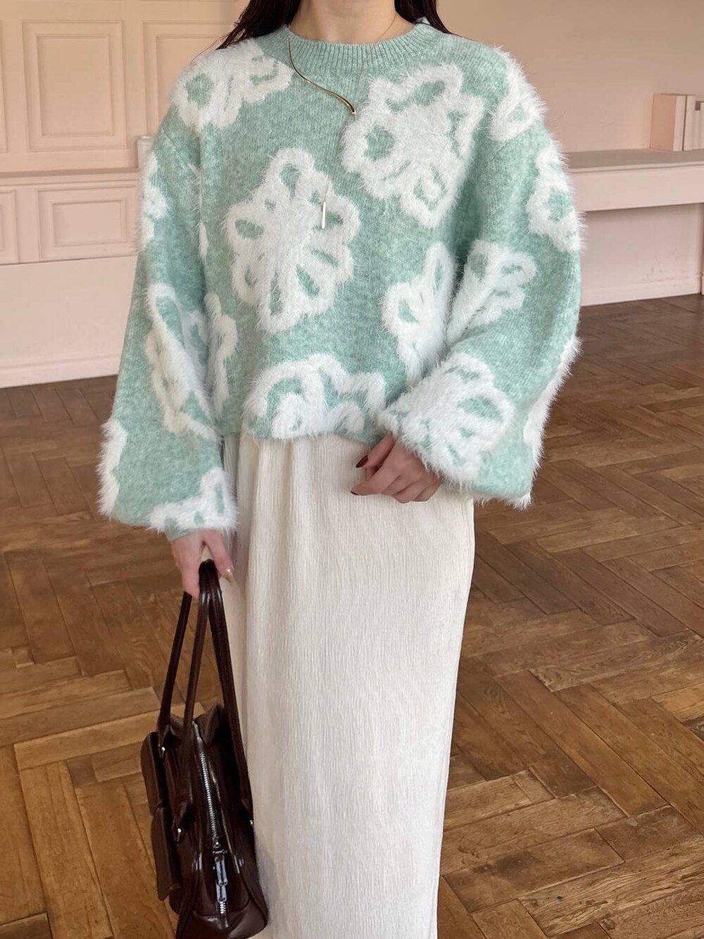 グリーン系のニット/セーター、ブラウン系のブーツ、ホワイト系のスカートを着用したレディースの冬コーディネートの3枚目の写真