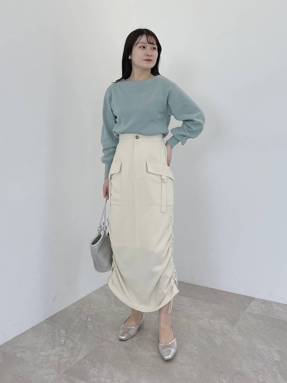 シルバー系のバレエシューズ、グリーン系のニット/セーター、ブラック系のトレンチコートを着用したレディースの冬コーディネートの4枚目の写真