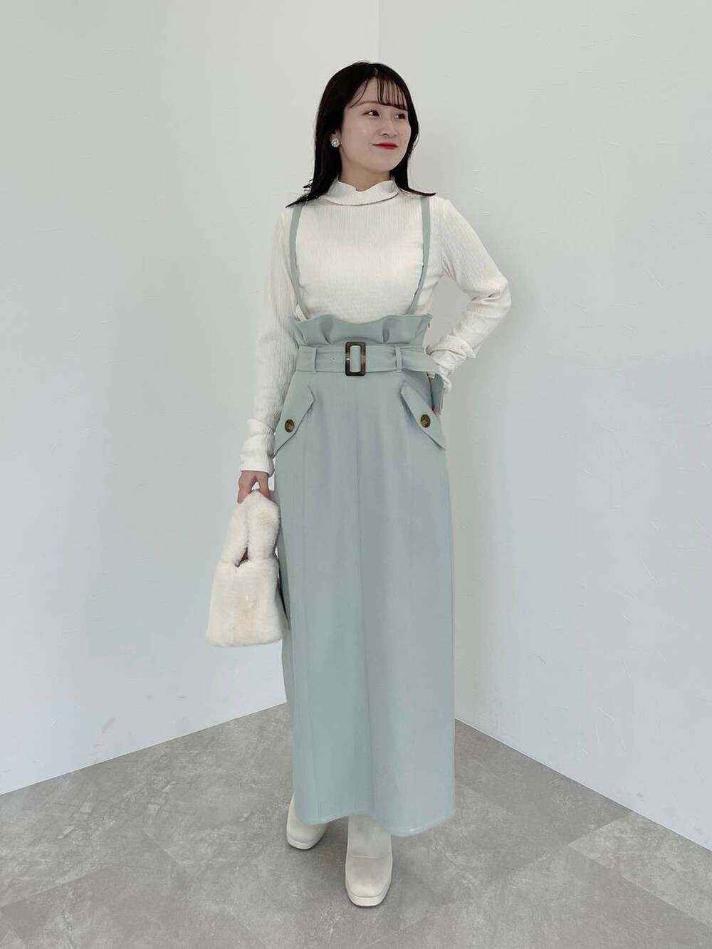 ホワイト系のブーツ、ホワイト系のハンドバッグ、ホワイト系のチェスターコートを着用したレディースの冬コーディネートの4枚目の写真