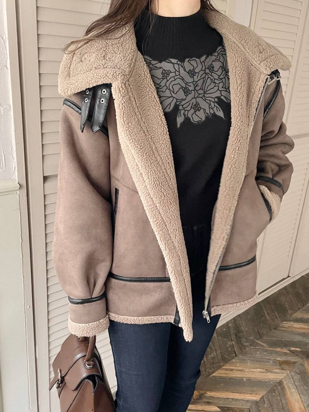 ブルー系のデニムパンツ、ブラウン系のハンドバッグ、ブラック系のブーツを着用したレディースの秋コーディネートの3枚目の写真