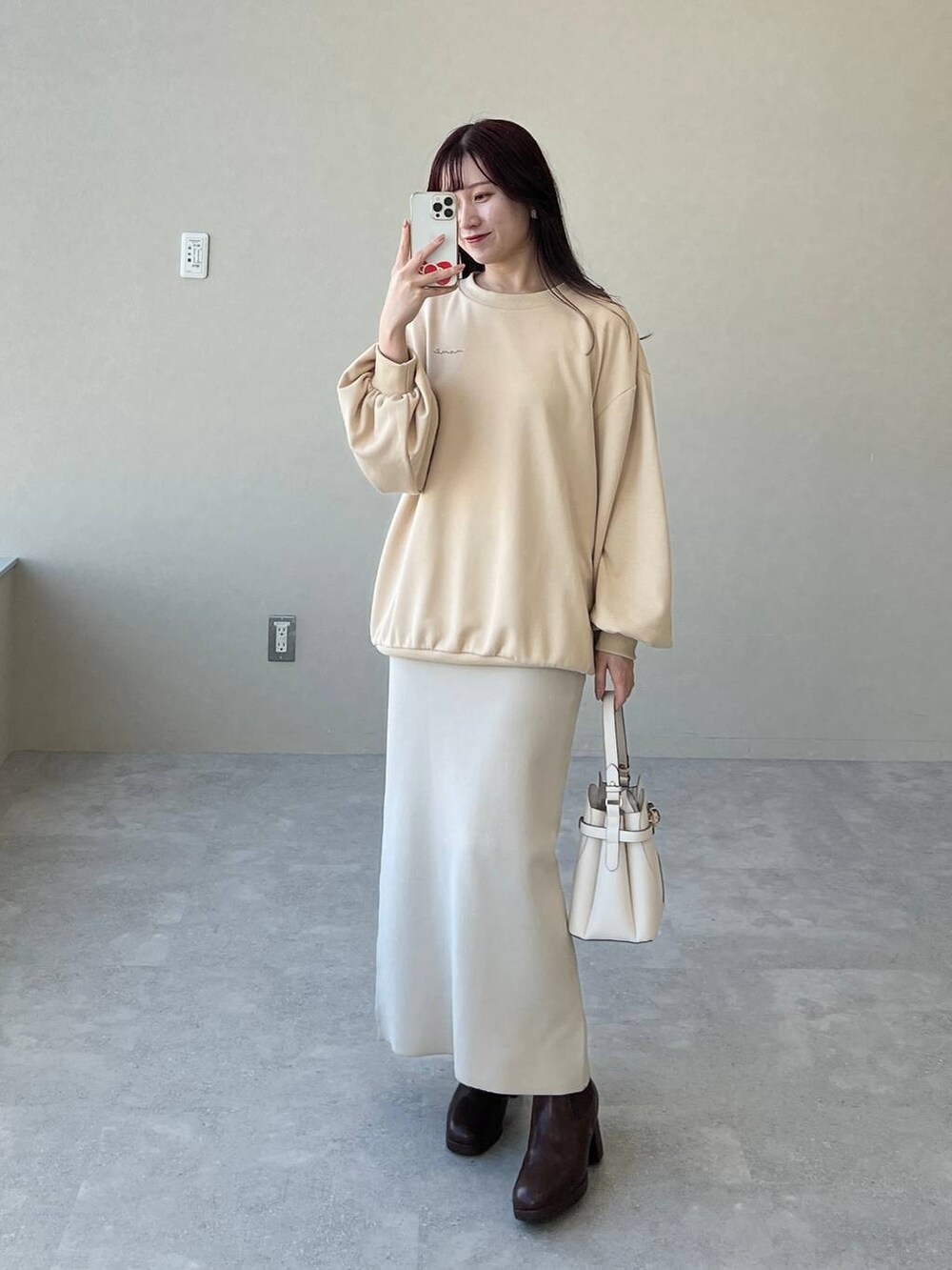 ホワイト系のショルダーバッグ、ブラウン系のブーツ、ベージュ系のスウェットを着用したレディースの冬コーディネートの3枚目の写真