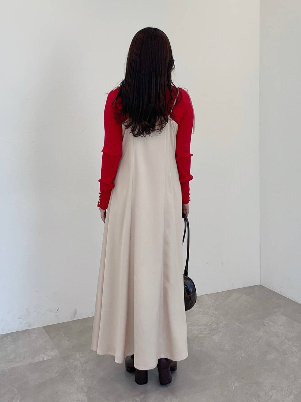 ブラウン系のブーツ、レッド系のニット/セーター、ブラウン系のハンドバッグを着用したレディースの冬コーディネートの2枚目の写真