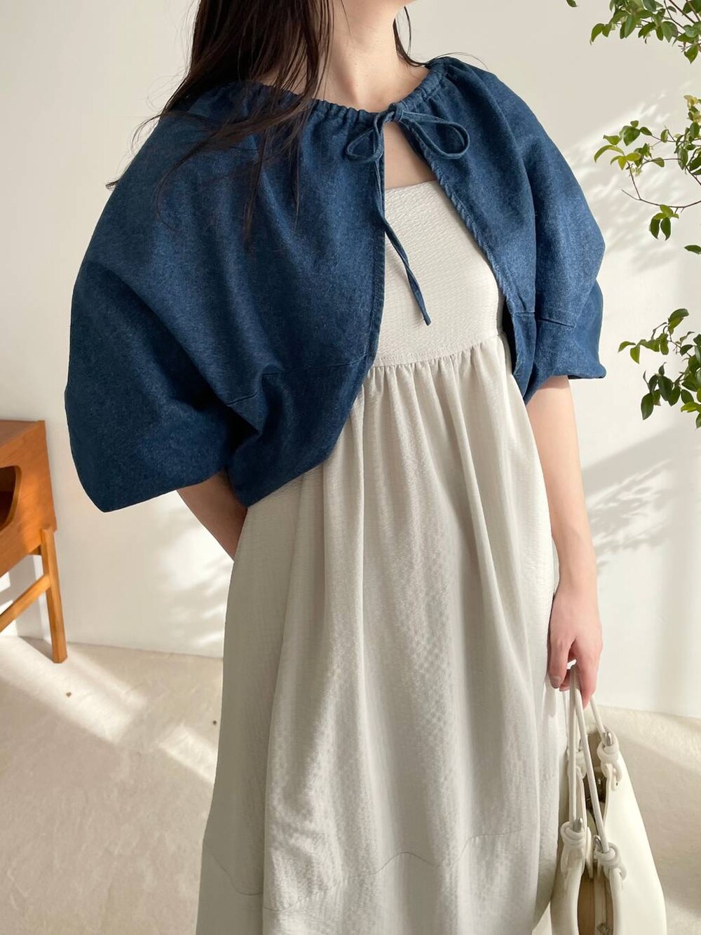 ブルー系のアンサンブル、ホワイト系のハンドバッグ、グレー系のワンピースを着用したレディースの春コーディネートの3枚目の写真
