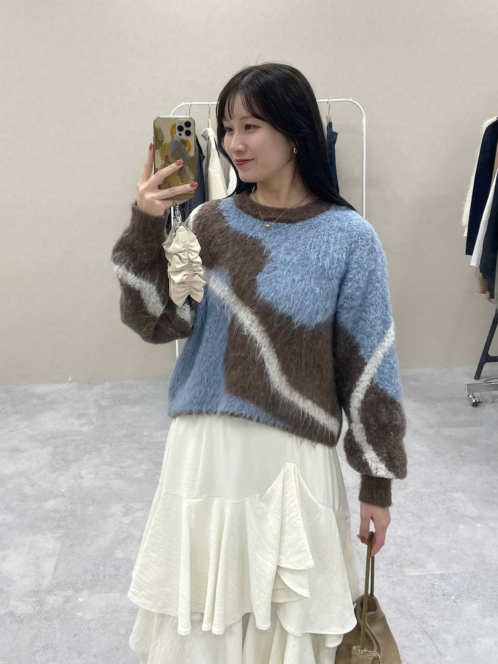 ブラウン系のニット/セーター、ホワイト系のスカート、ブラック系のローファーを着用したレディースの秋コーディネートの4枚目の写真