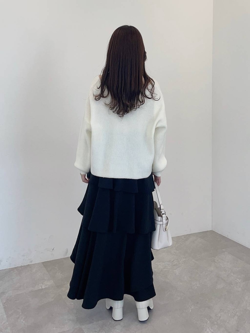 ホワイト系のショルダーバッグ、ホワイト系のブーツ、ブラック系のスカートを着用したレディースの冬コーディネートの2枚目の写真