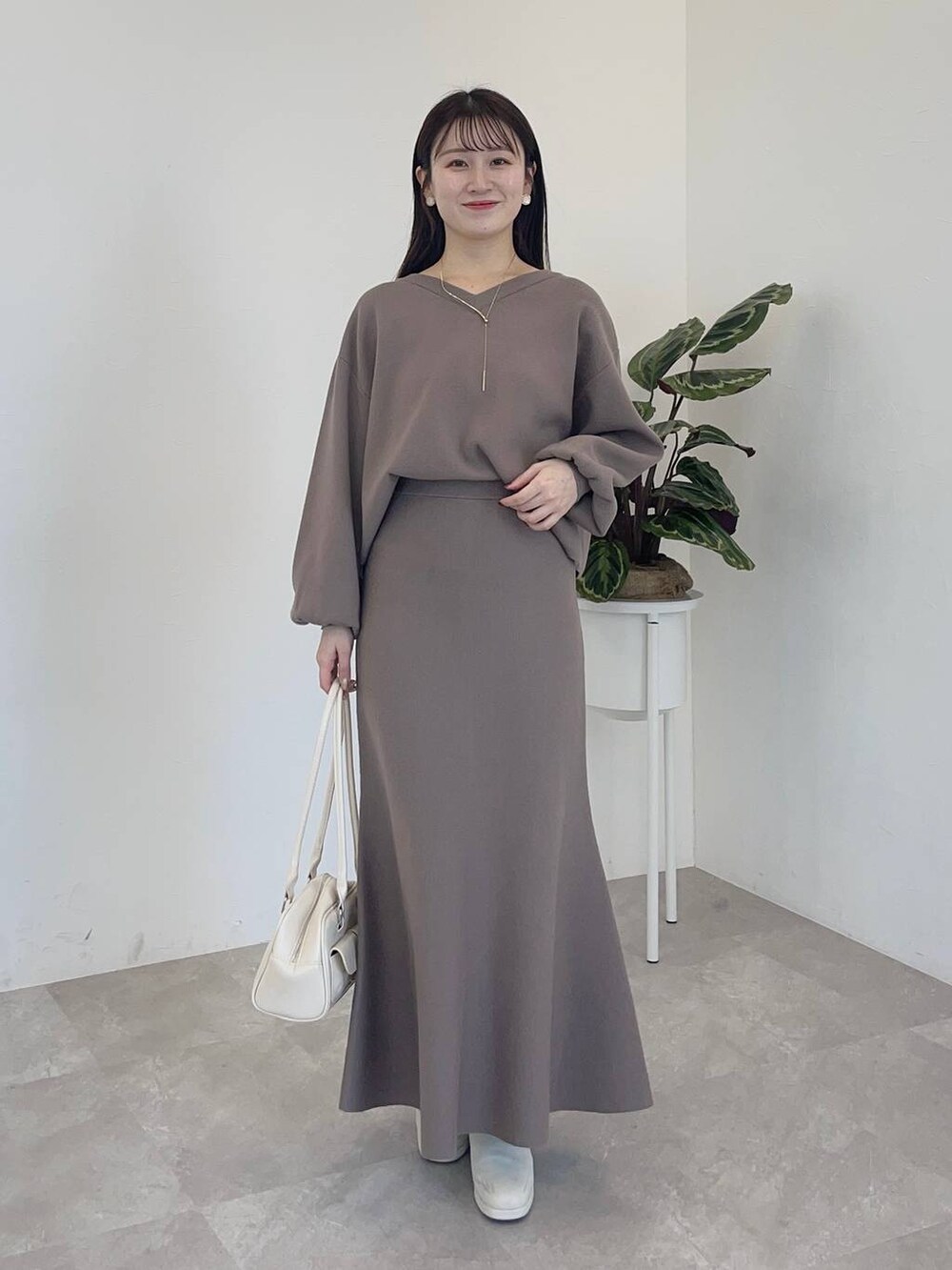 ホワイト系のチェスターコート、ホワイト系のブーツ、ホワイト系のハンドバッグを着用したレディースの冬コーディネートの3枚目の写真