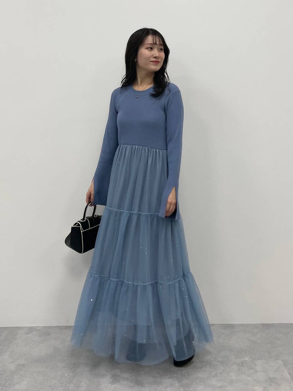 ブルー系のノーカラーコート、ブラック系のハンドバッグ、ブラック系のブーツを着用したレディースの秋コーディネートの4枚目の写真