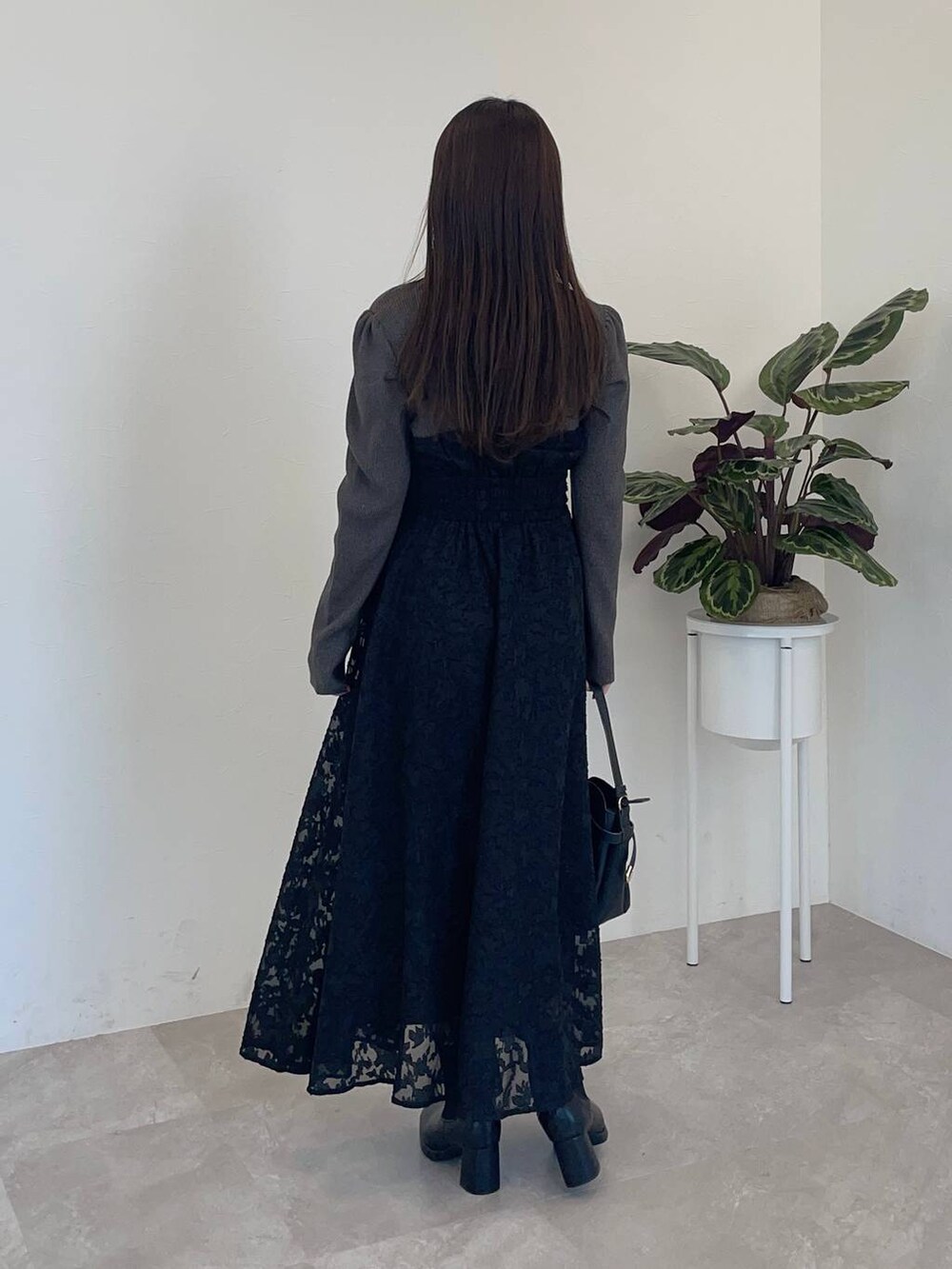 グレー系のノーカラーコート、ブラック系のショルダーバッグ、ブラック系のブーツを着用したレディースの冬コーディネートの4枚目の写真