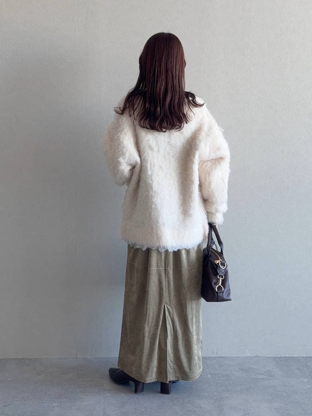 ブラウン系のボストンバッグ、ベージュ系のワンピース、ブラウン系のブーツを着用したレディースの冬コーディネートの2枚目の写真